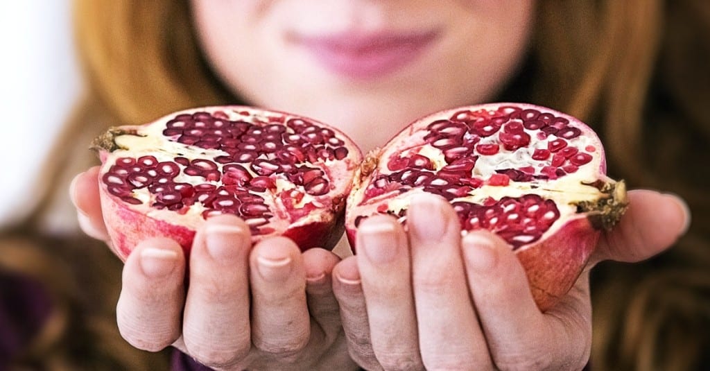 Frau hat zwei Granatäpfel in der Hand