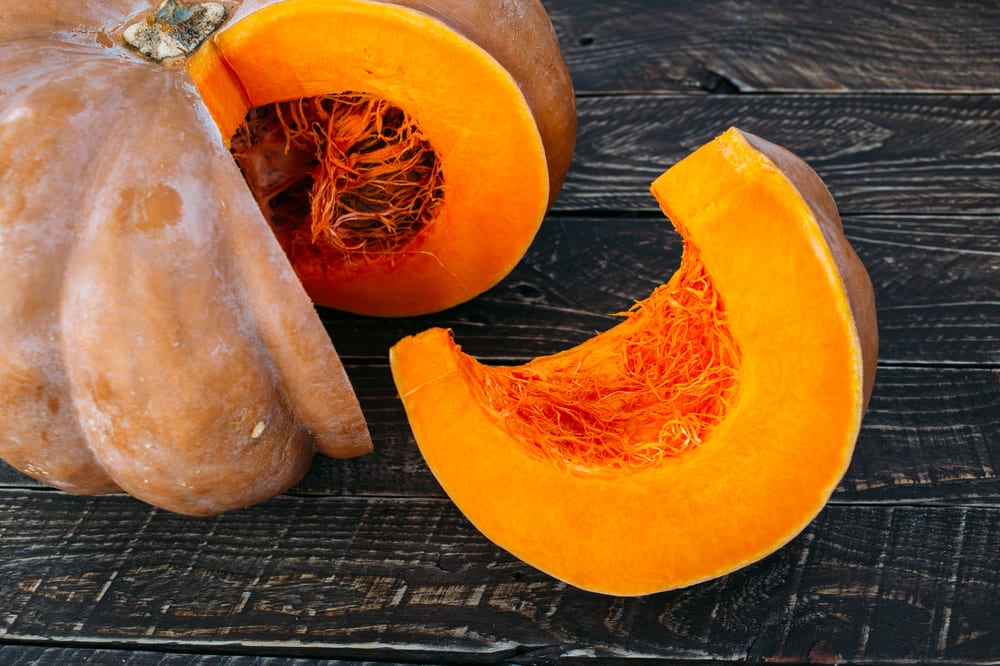 Der aufgeschnittene Muskatkürbis zeigt sein leuchtendes Kürbisfleisch.