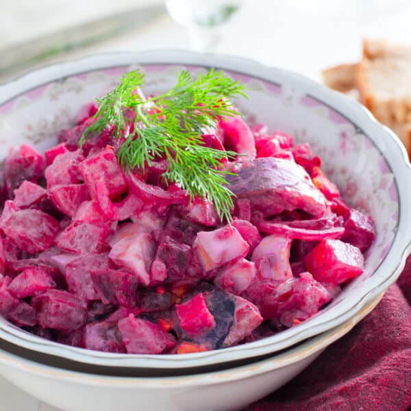 Festlich angerichteter Rollmops-Salat mit roter Bete, Apfel und Dill, serviert in einer dekorativen Schale.