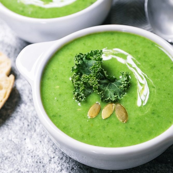 Vegetarische Grünkohlsuppe in einer Schale, dekoriert mit karamellisierten Zwiebeln und Chiliflocken.