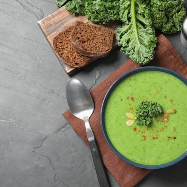 Vegetarische Grünkohlsuppe in einer Schale, dekoriert mit karamellisierten Zwiebeln und Chiliflocken.