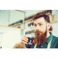 Barista-Kurs-Gutschein – Mann mit Bart riecht an Kaffee