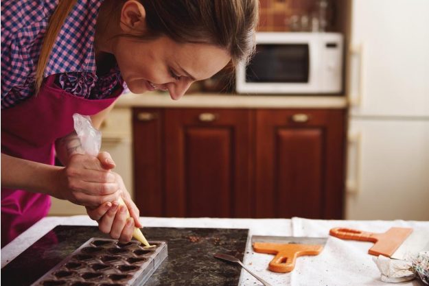 Pralinenkurs München – Frau gießt Schokolade in Form
