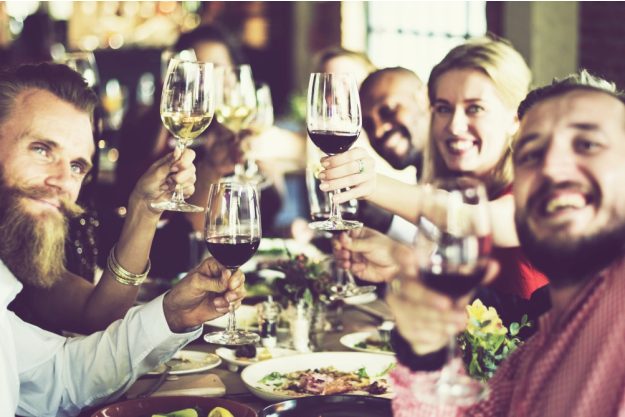 Kulinarisches Firmenevent – Lachende Kursteilnehmer stoßen mit Wein an