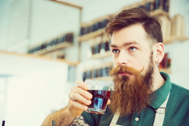 Barista-Kurs-Gutschein – Mann mit Bart riecht an Kaffee